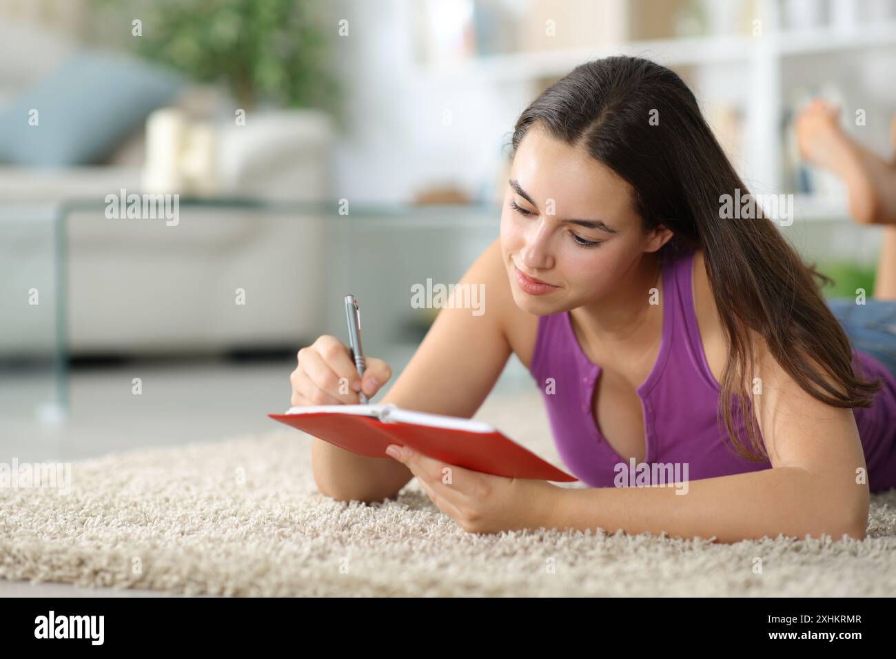 Femme écrit dans l'agenda sur le sol à la maison Banque D'Images