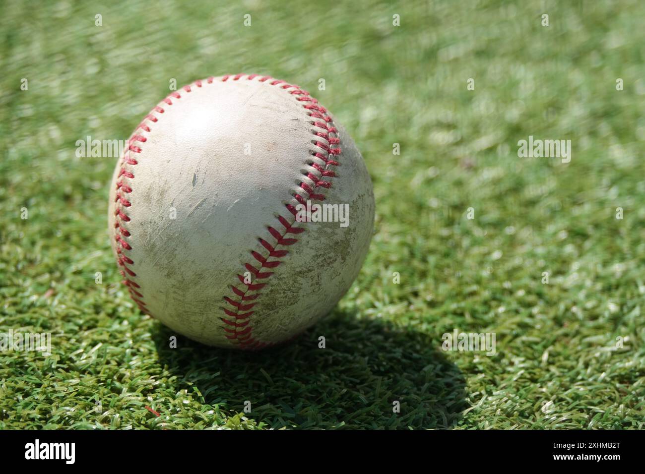 Une vieille balle de baseball repose sur le terrain d'herbe verte Banque D'Images