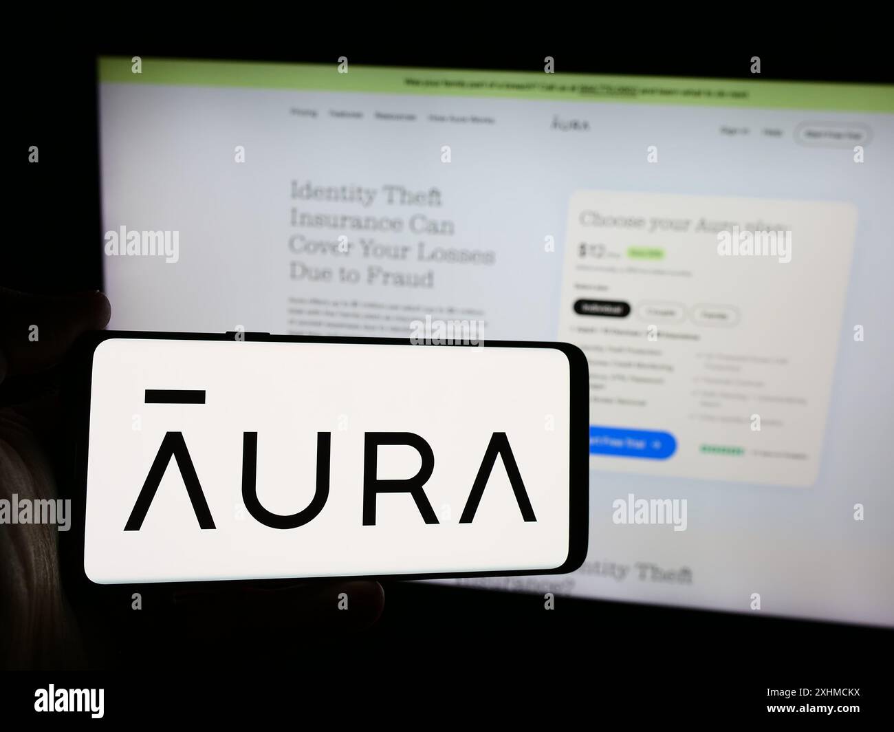 Personne tenant un smartphone avec le logo de la société américaine de logiciels de cybersécurité aura Sub LLC en face du site Web. Concentrez-vous sur l'affichage du téléphone. Banque D'Images