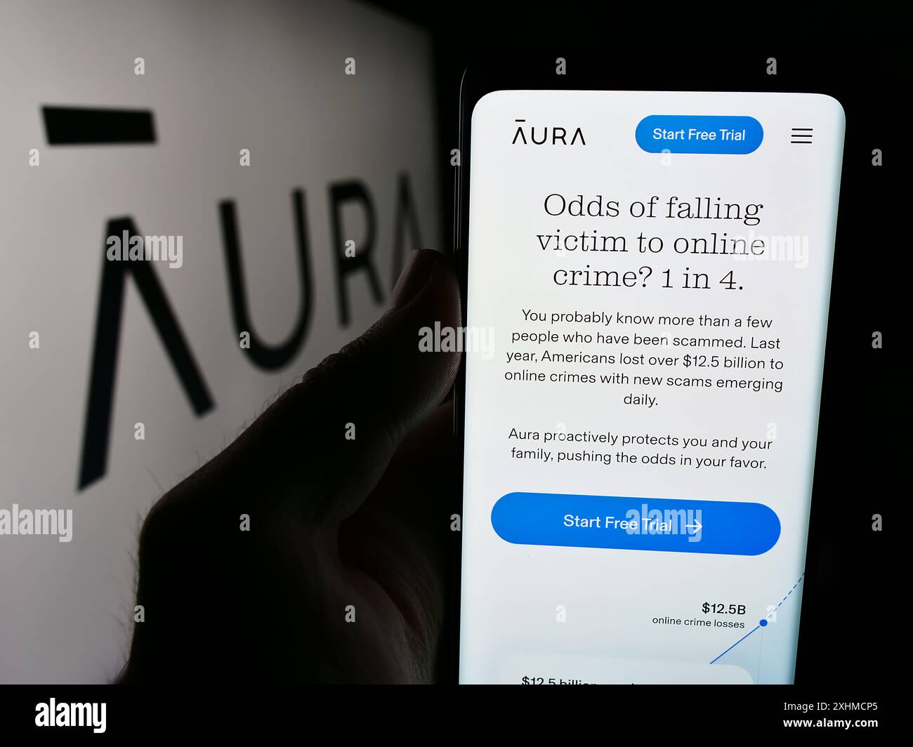 Personne tenant un téléphone portable avec le site Web de la société américaine de logiciels de cybersécurité aura Sub LLC devant le logo. Concentrez-vous sur le centre de l'écran du téléphone. Banque D'Images