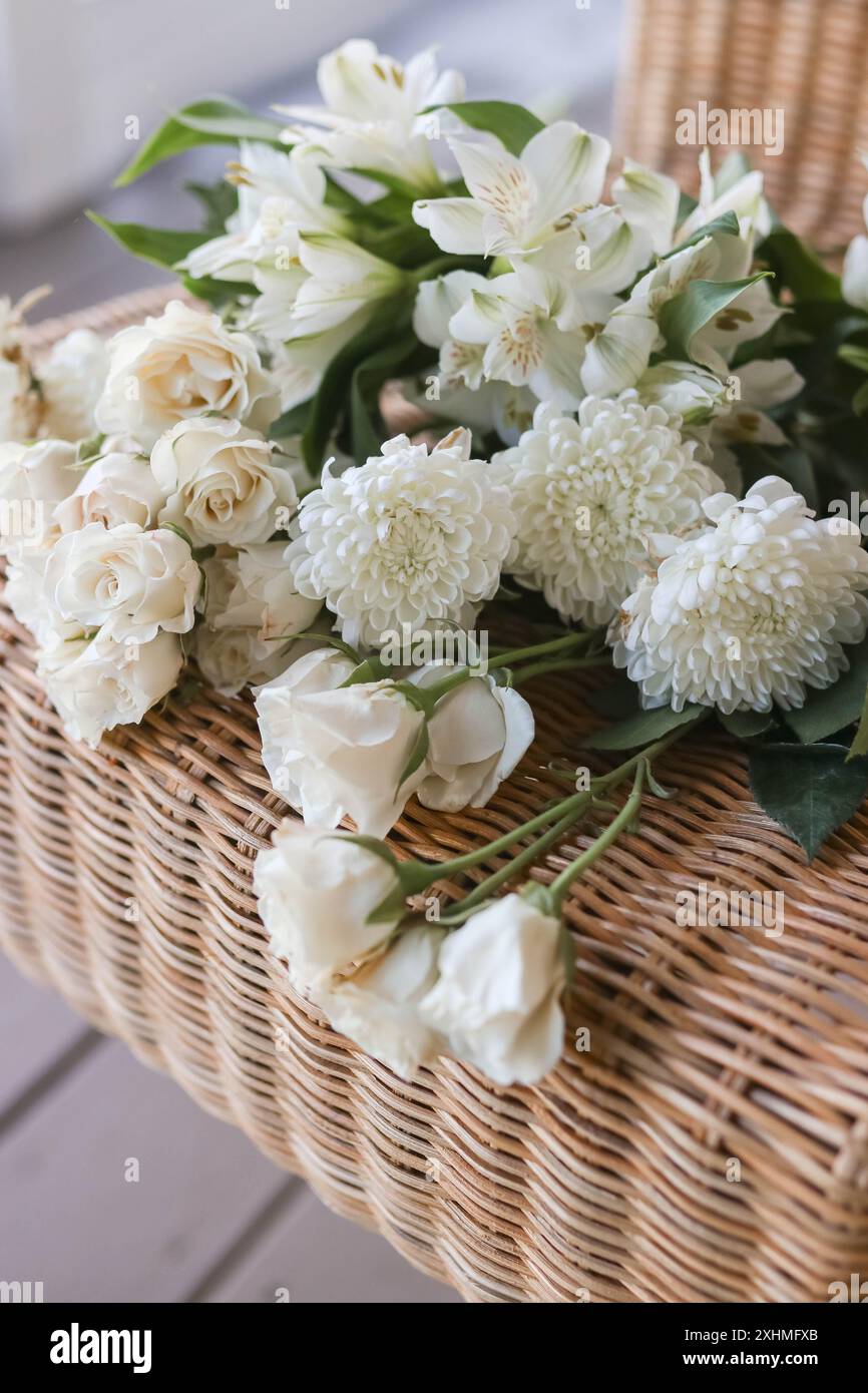 Ensemble de fleurs blanches crémeuses exposé sur Une chaise en rotin Banque D'Images