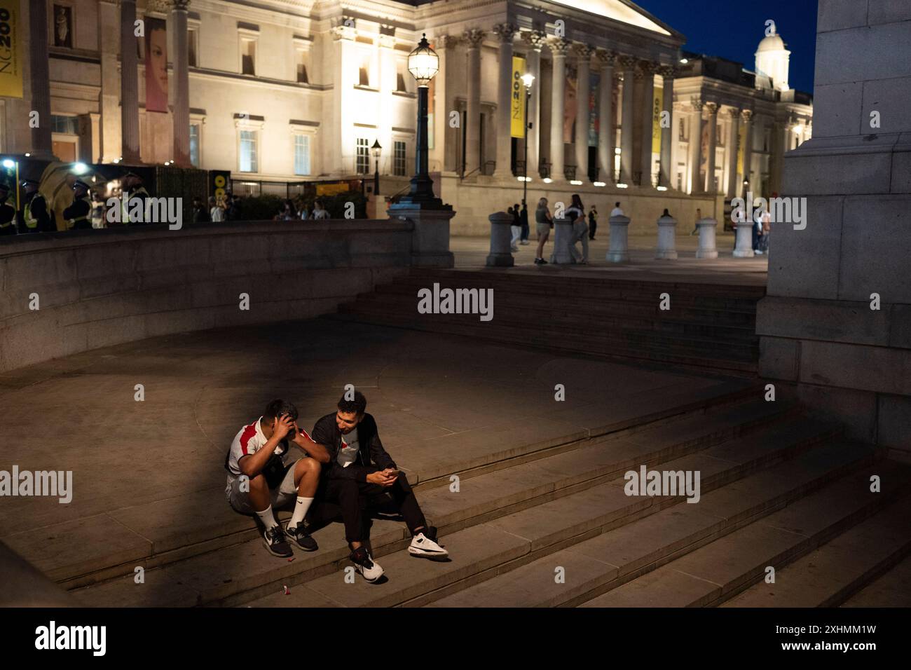Deux fans de football anglais abattus sont assis sur les marches à Trafalgar Square lors d'une opération de police en cas de désordre de foule dans les heures qui ont suivi la défaite de l'Angleterre contre l'Espagne lors de la finale de la coupe de l'UEFA, le 14 juillet 2024 à Londres, Angleterre. Aucun problème n'a été signalé et les fans de football sont en grande partie rentrés chez eux tranquillement. Banque D'Images
