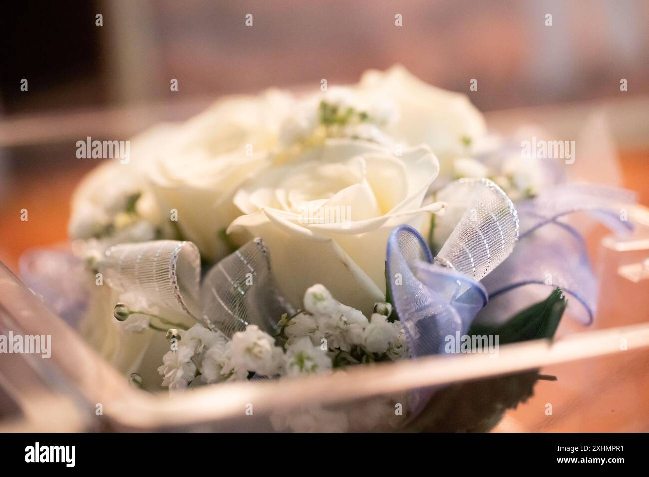 Gros plan d'un corsage de bracelet pour le bal, avec des roses blanches et un ruban bleu Banque D'Images