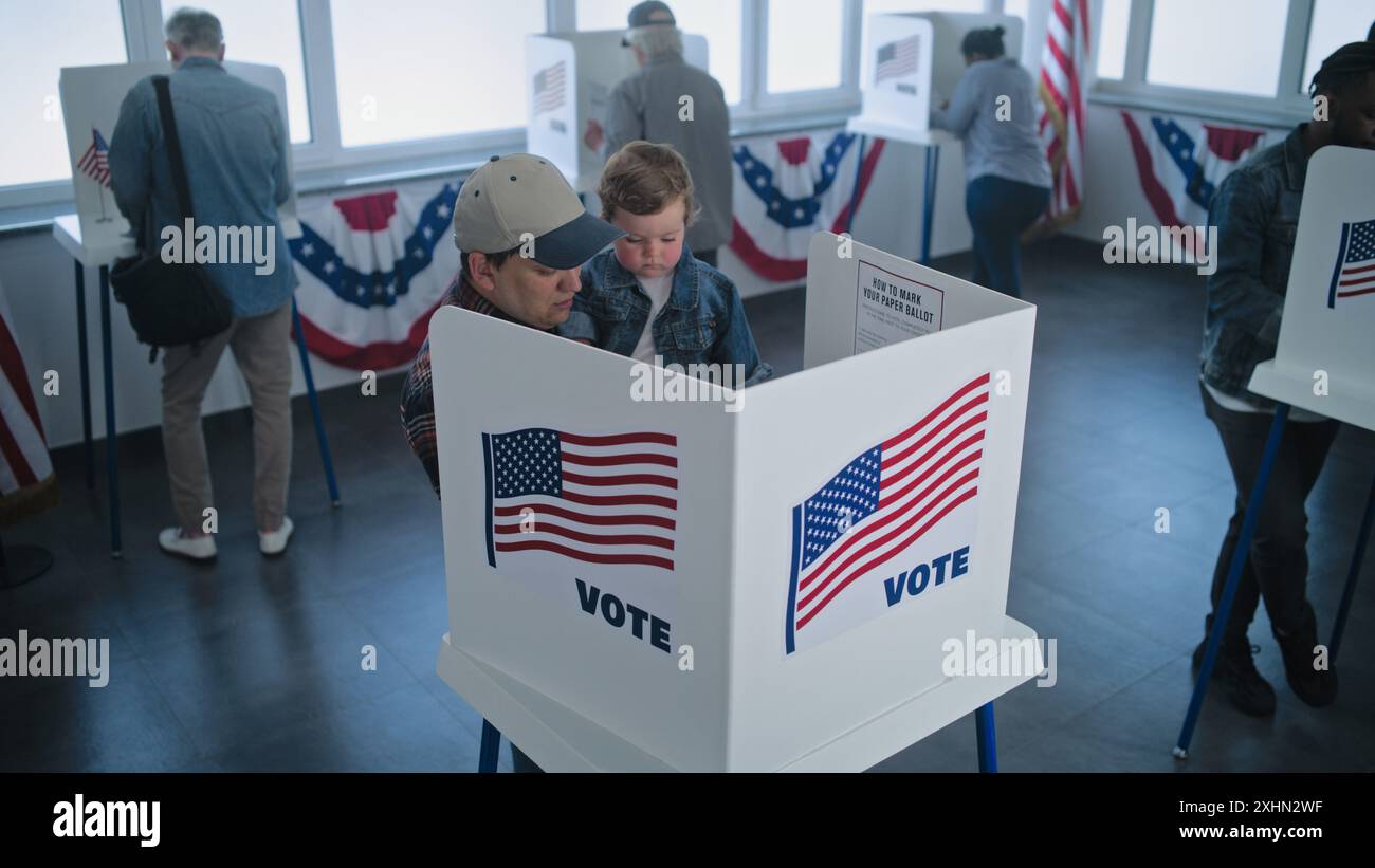 Un homme caucasien avec son fils entre dans la cabine de vote pour remplir le bulletin de vote. Divers citoyens américains et électeurs américains votent au bureau de vote. Élections présidentielles aux États-Unis. Concept de démocratie. Banque D'Images