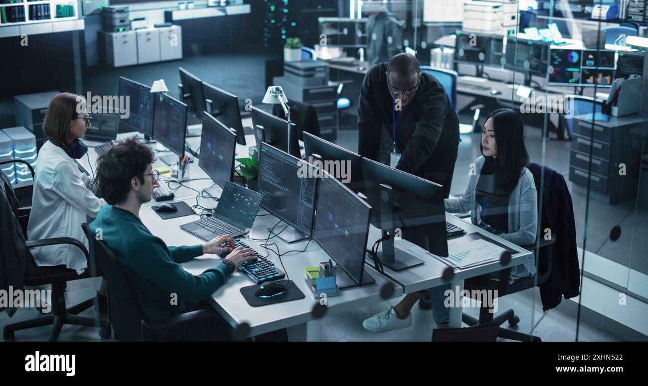 Groupe d'hommes et de femmes multiculturels autonomisés travaillant dans un centre de recherche, utilisant des ordinateurs pour exécuter des logiciels avancés, développer une interface d'intelligence artificielle et une chaîne de blocs de Cloud Computing Banque D'Images