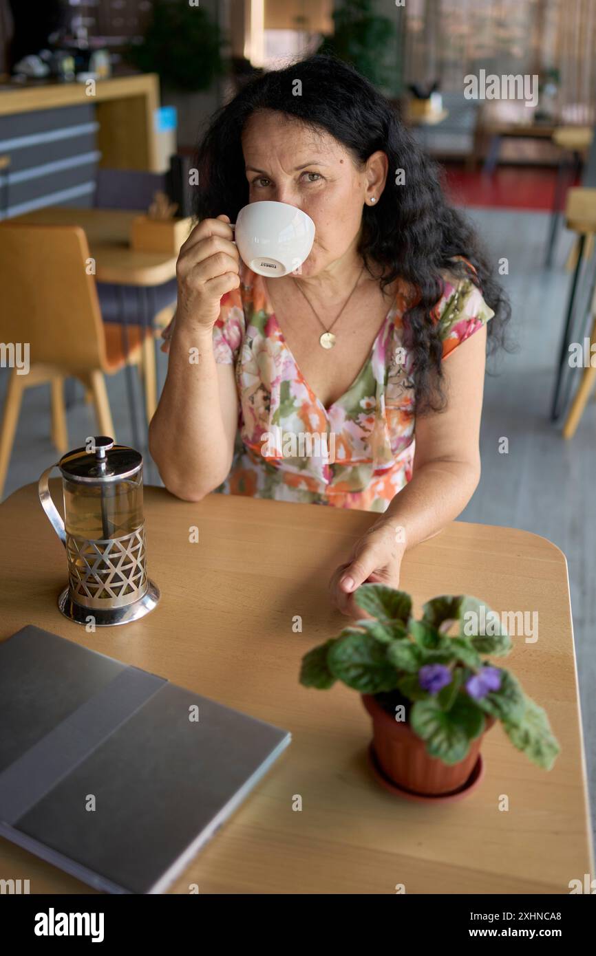 une femme des années 60 buvant du thé d'ortie dans un bureau de coworking moderne pendant la pause déjeuner Banque D'Images