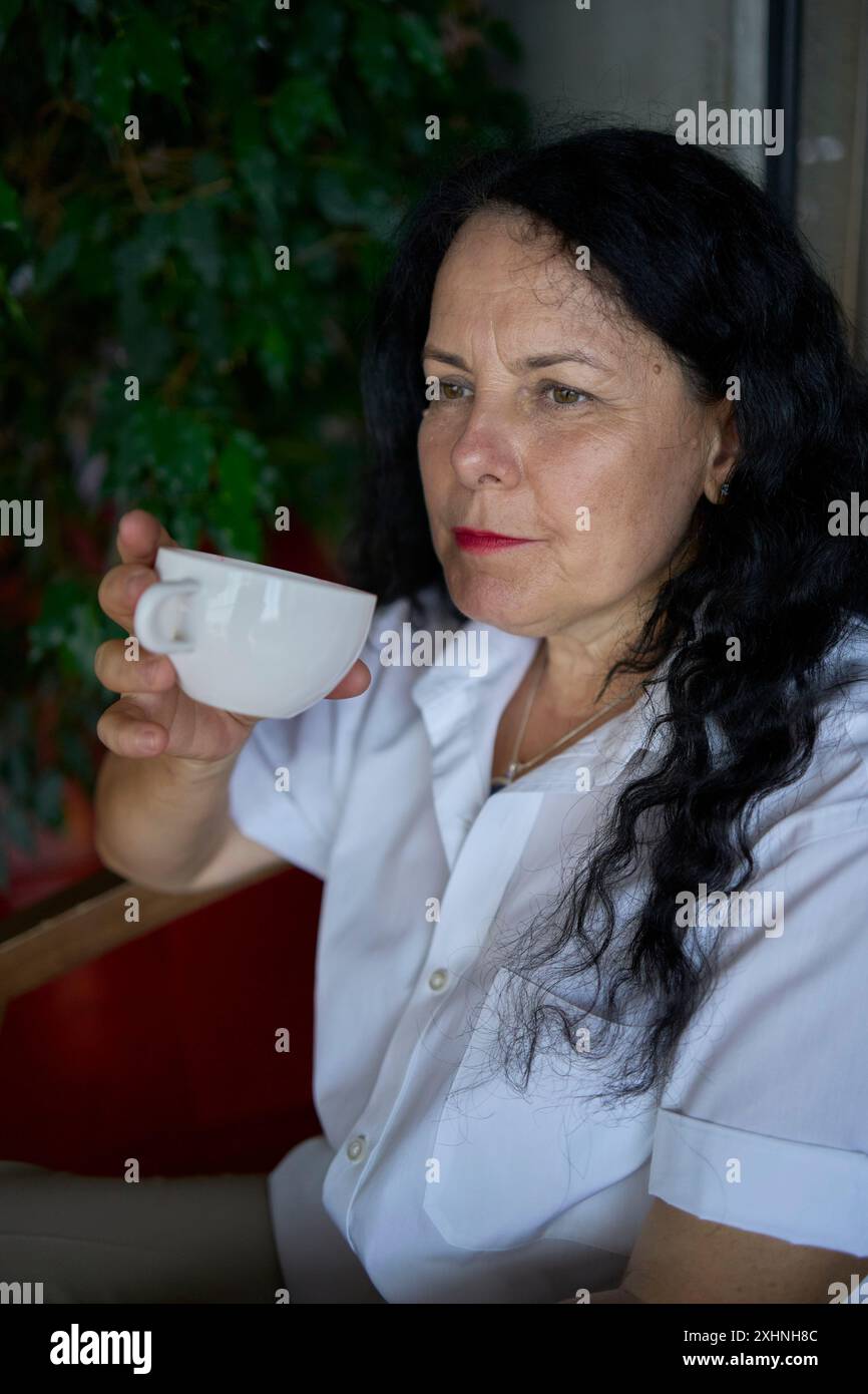 une femme des années 60 buvant du thé d'ortie dans un bureau de coworking moderne pendant la pause déjeuner Banque D'Images