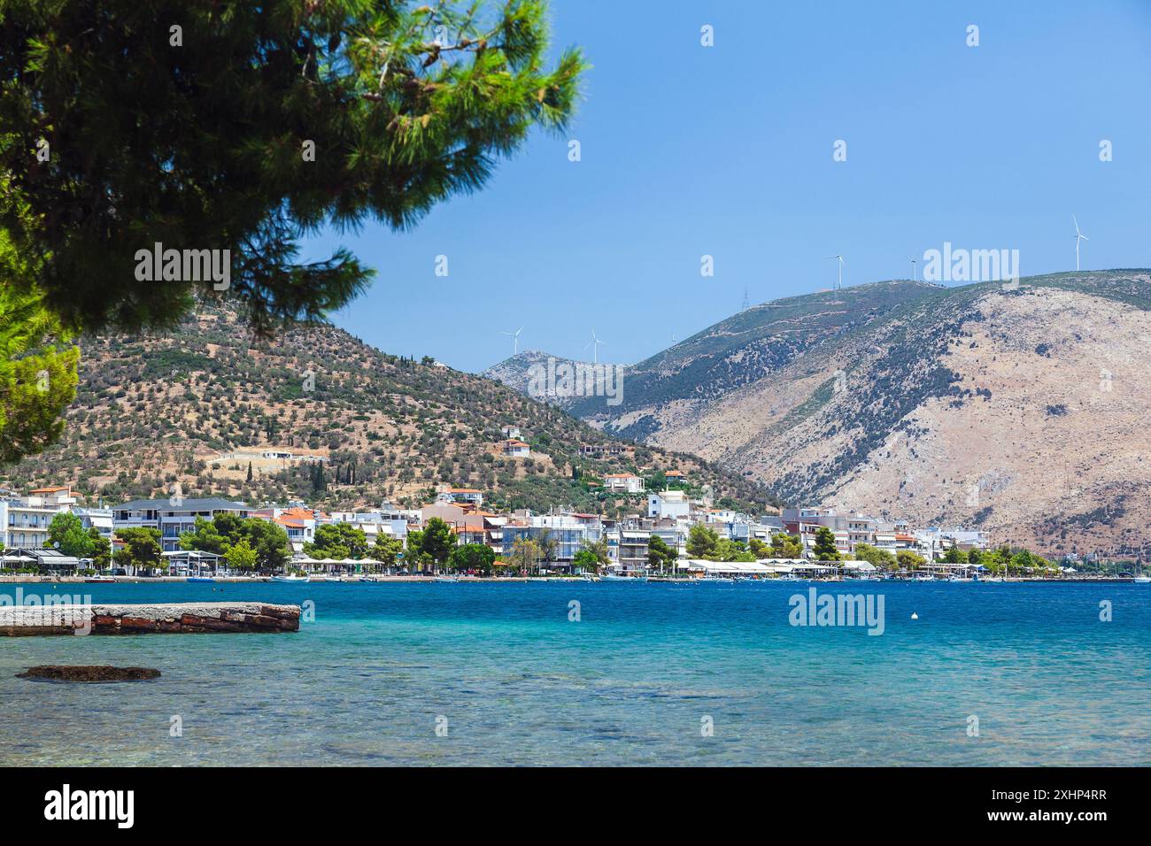 Vue panoramique d'Antikyra, Béotie, Grèce, avec front de mer pittoresque, verdure luxuriante, et des collines ondulantes sous un ciel bleu vif. Banque D'Images