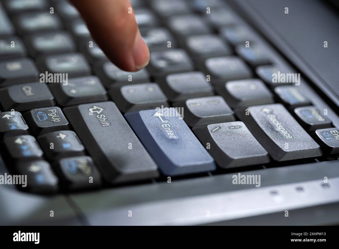 Mans doigt sur le point d'appuyer sur une touche entrée sur un clavier d'ordinateur portable de bureau moderne, main planant au-dessus de la touche entrée, homme indécis prêt à pousser t Banque D'Images