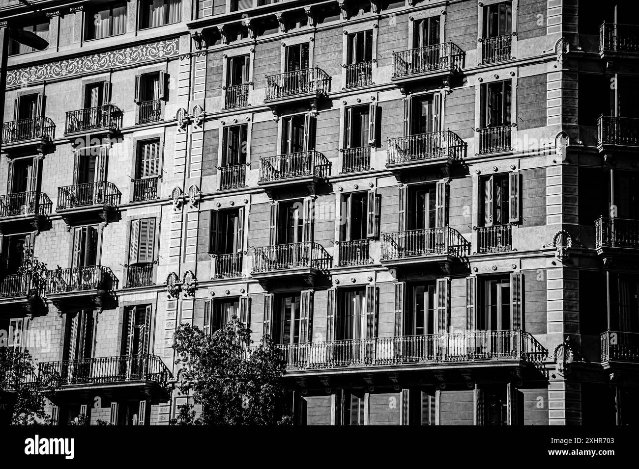 Noir et blanc de la façade avant d'un immeuble à Barcelone, Espagne, avec de nombreuses fenêtres, balcons, volets en bois Banque D'Images