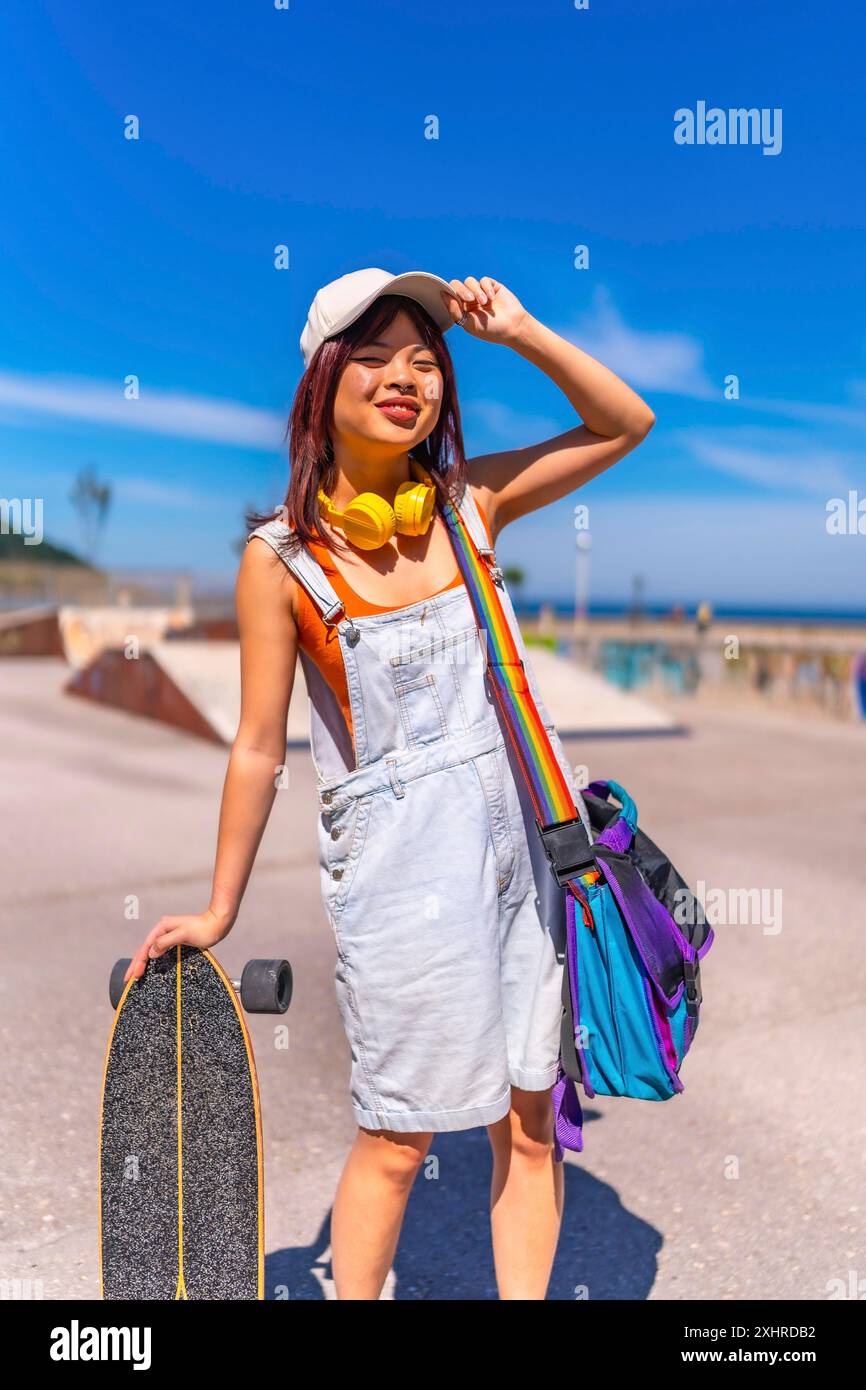 Portrait vertical d'une adolescente chinoise asiatique avec sa planche à roulettes dans un parc public se préparant à patiner Banque D'Images