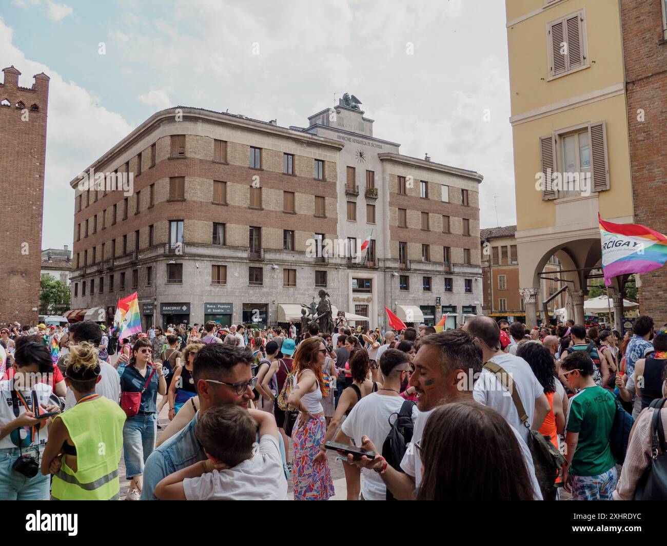 Foule rassemblée devant un bâtiment avec divers drapeaux lors d'un événement urbain d'été, éditorial gay Pride cremona italie 6 juillet 2024 Banque D'Images