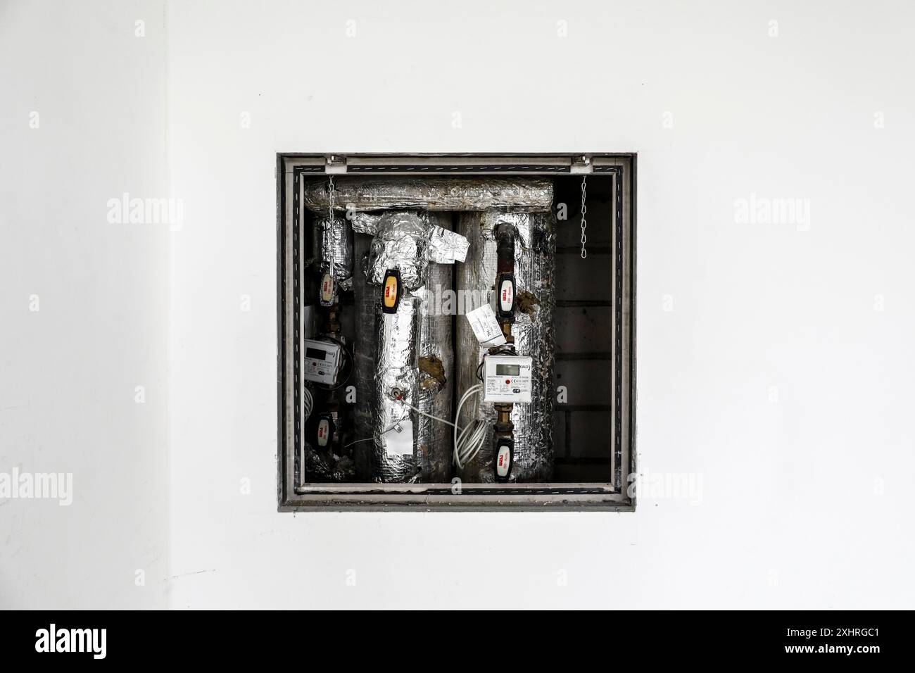 Les tuyaux isolés et les appareils de mesure d'un système de chauffage peuvent être vus derrière un mur blanc, Berlin, 15.04.2024., Berlin, Berlin, Berlin, Allemagne Banque D'Images
