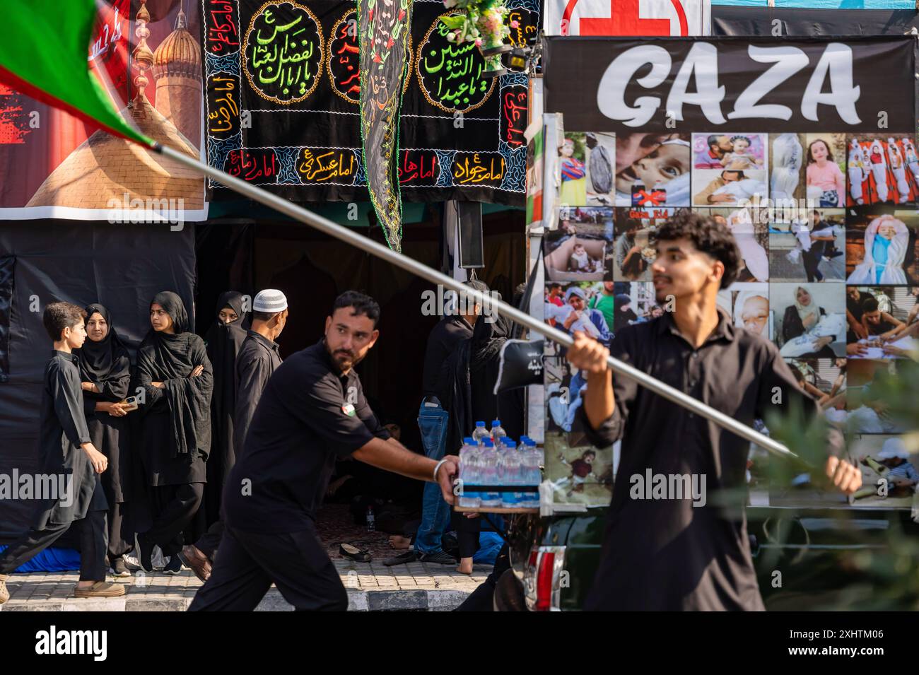 Les femmes musulmanes chiites du Cachemire regardent les personnes en deuil marcher avec des drapeaux et des banderoles palestiniens lors d'une procession le huitième jour de Mouharram. Pour la deuxième année consécutive, l'administration du Jammu-et-Cachemire a autorisé la 8e procession de Muharram à se rendre de Guru Bazar à Dalgate à Srinagar. Malgré une interdiction de longue date, les musulmans chiites avaient continué à organiser des processions les 8 et 10 Muharram le long de ces routes, souvent confrontées à une action policière. La procession de cette année a marqué une commémoration importante et pacifique du martyre de Hazrat Imam Hussainís (AS), attirant des milliers de personnes en deuil. Le proc Banque D'Images