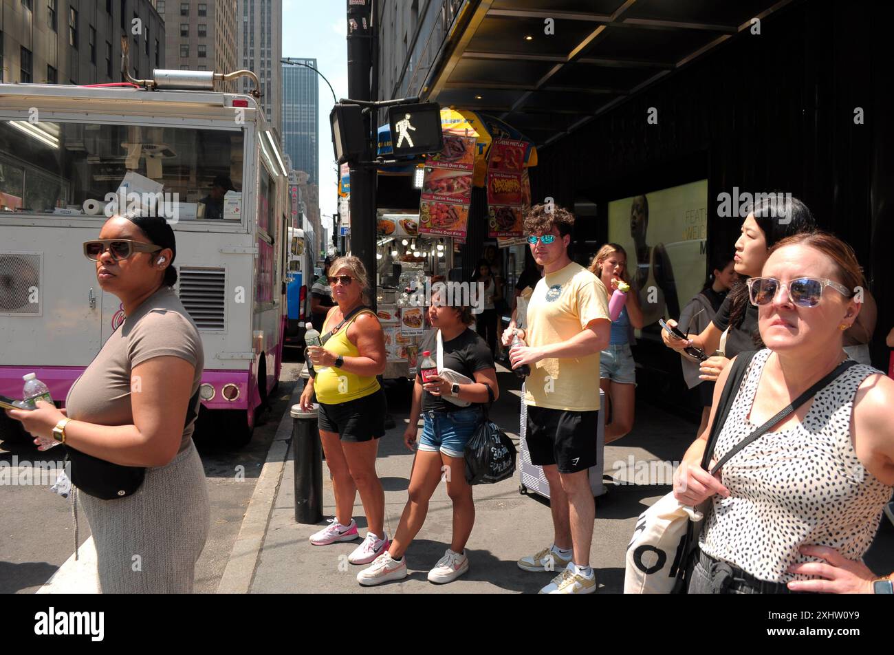 New York, États-Unis. 15 juillet 2024. Les gens se tiennent dans la rue pendant la troisième vague de chaleur de l'été à Manhattan, New York. Les New-Yorkais connaissent des températures élevées dans les années 90 avec un temps humide qui rend le temps plus chaud. Les avis météorologiques incitent les gens à rester au frais et hydratés par temps chaud. Crédit : SOPA images Limited/Alamy Live News Banque D'Images