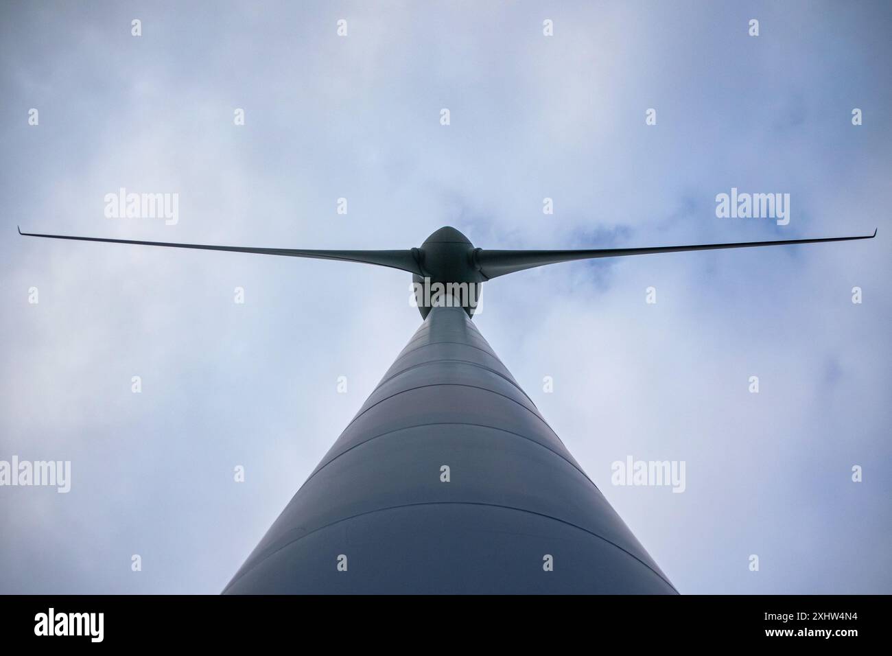 Cette image capture une vue rapprochée et à bas angle d'une éolienne moderne installée sur un ciel bleu clair. La conception élégante et aérodynamique de la turbine b Banque D'Images