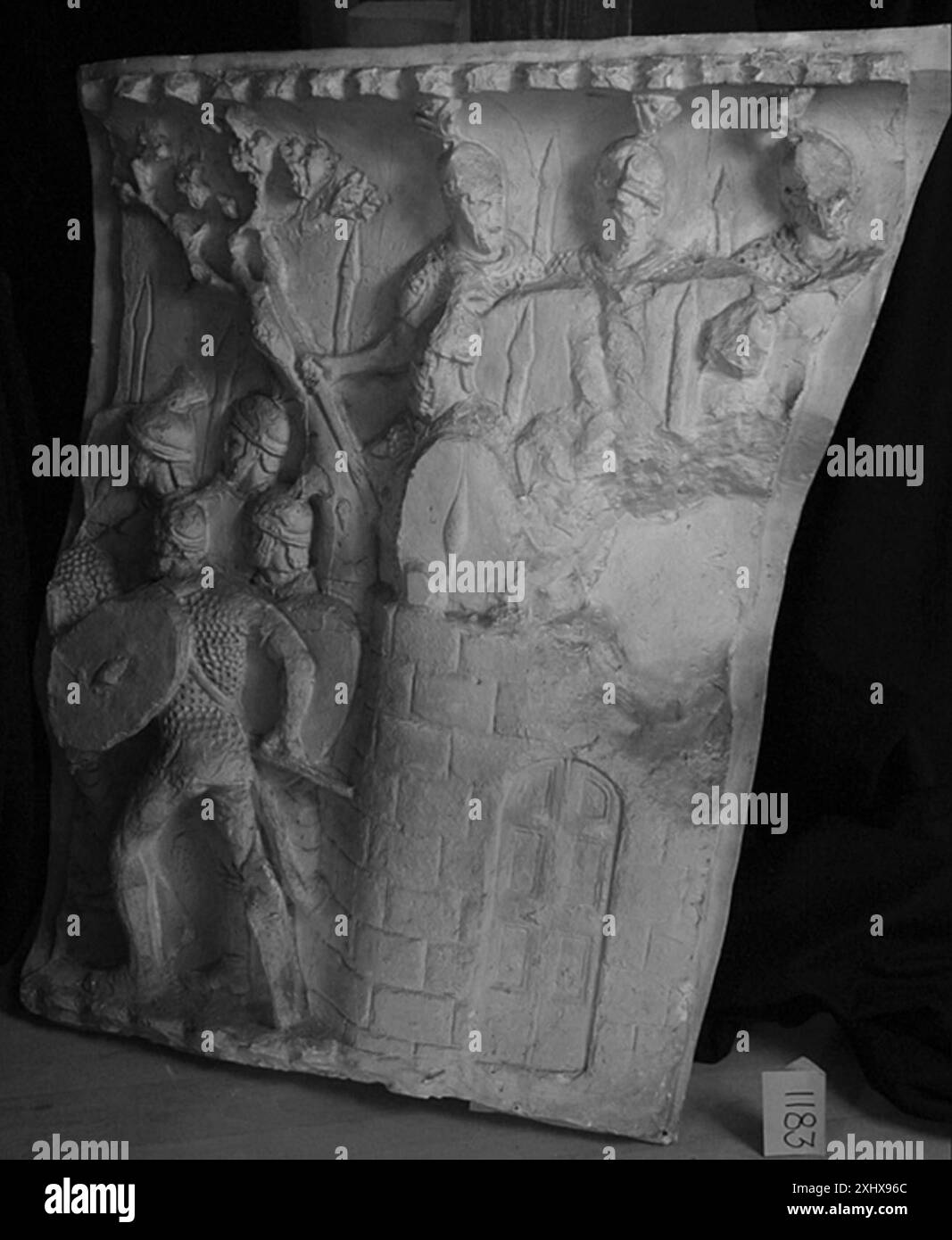 Relief représentant un soldat romain sortant d'un fort tandis que trois soldats supplémentaires sont visibles au-dessus du mur, illustrant l'action militaire. Banque D'Images