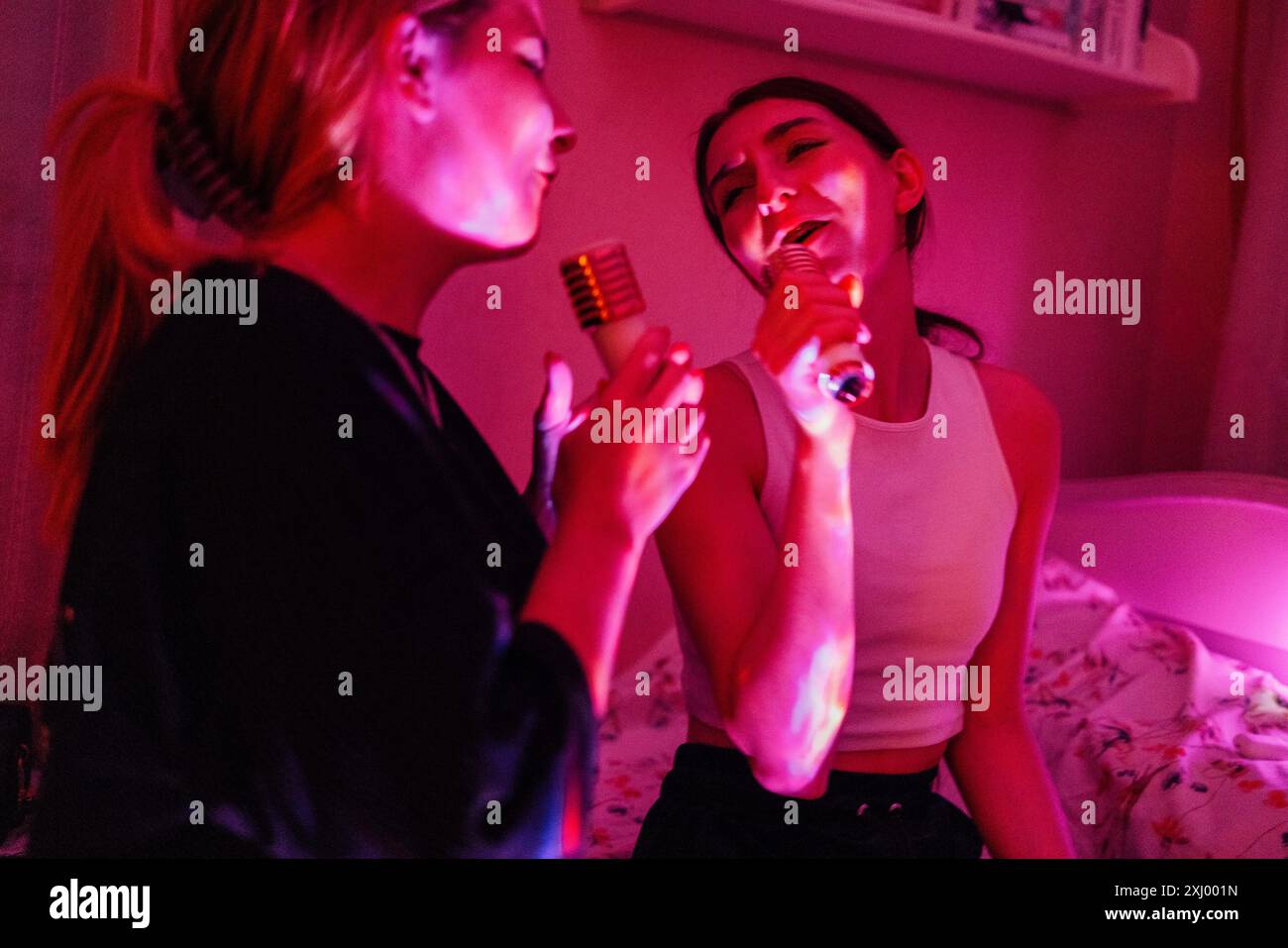 Deux adolescents mignons chantent des chansons de karaoké à la maison. De charmants amis dans des vêtements décontractés s'amusent ensemble. De jolis ados à une fête à la maison Banque D'Images