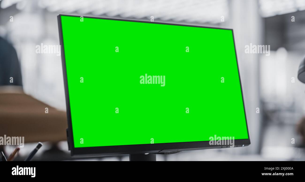 Gros plan d'un moniteur d'ordinateur de bureau avec écran vert maquette d'affichage debout dans Automotive Design Studio. Concept d'agence créative travaillant pour Automotive Factory. Poste de travail d'un employé. Banque D'Images