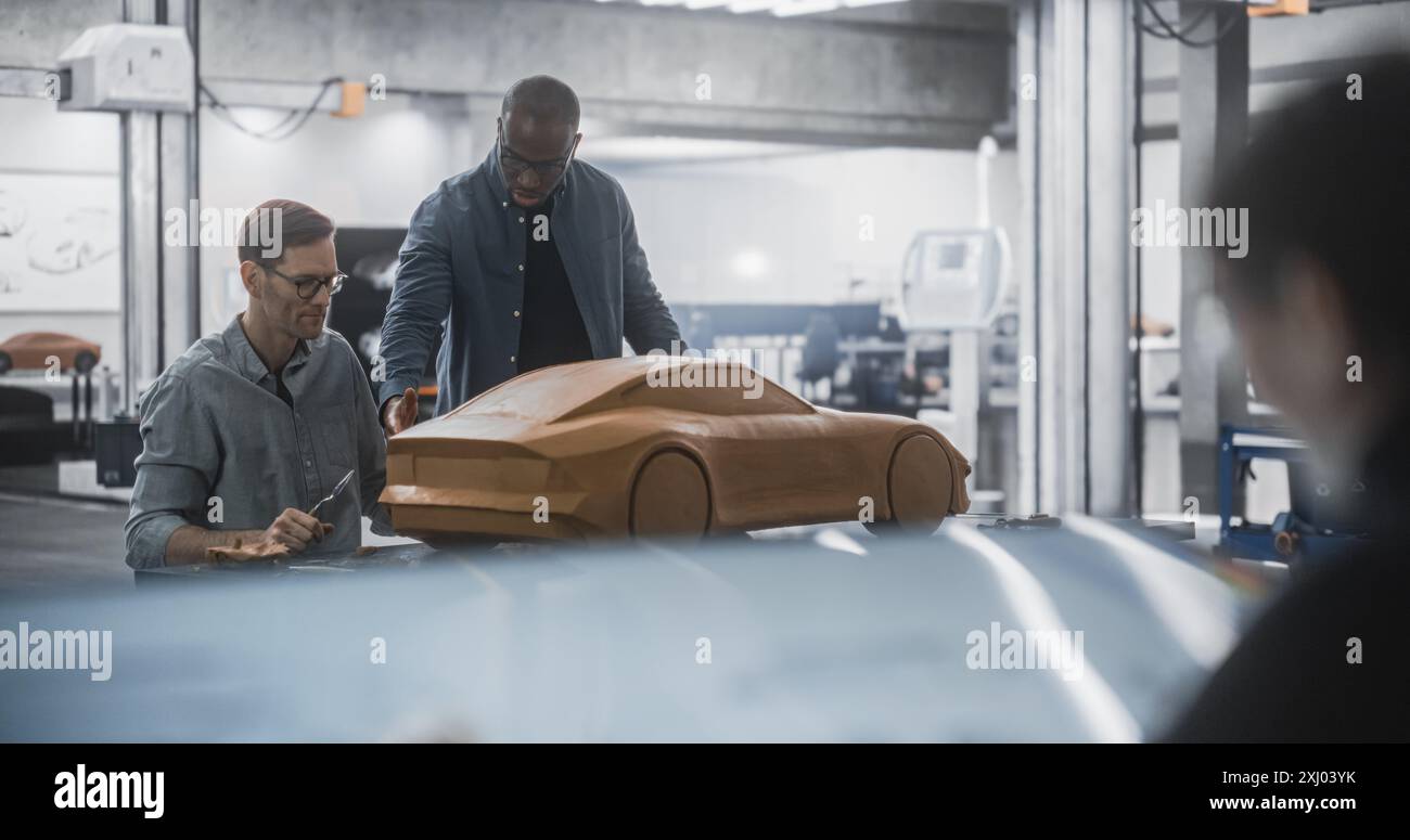 Femme dessinant un croquis de véhicule sur une tablette numérique. Clay car Modeler conseille un ingénieur aérodynamique sur la création d'un modèle polymère 3D d'une voiture électrique moderne. Équipe de spécialistes travaillant dans l'Agence Banque D'Images
