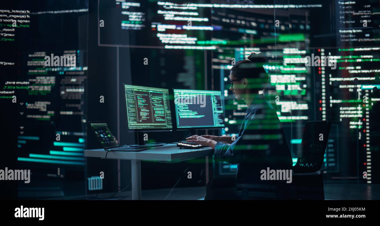 Programmeur féminin travaillant dans la salle de contrôle de surveillance, entouré de grands écrans affichant des lignes de code de langage de programmation. Portrait de femme créant un logiciel. Concept de codage futuriste abstrait Banque D'Images