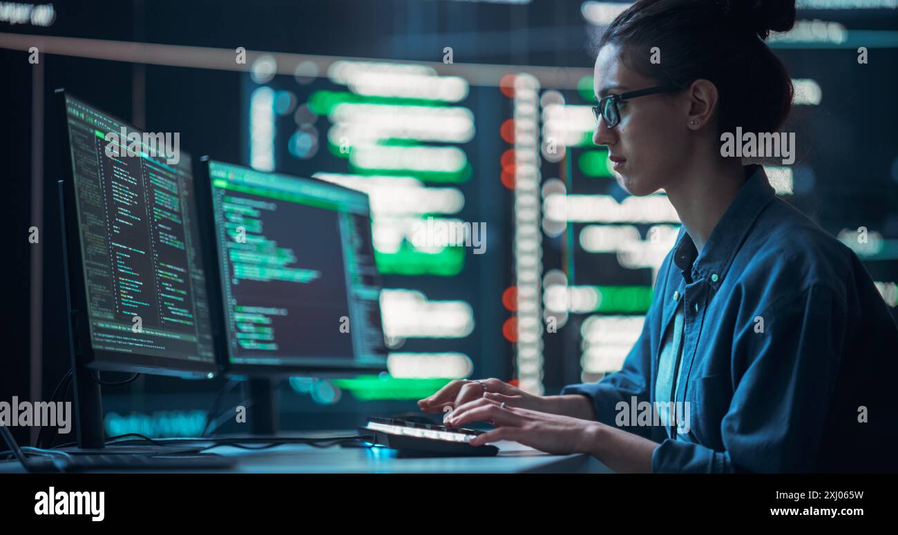 Plan moyen d'une femme travaillant comme développeur, entourée de grands écrans affichant des lignes de code dans une salle de surveillance. Programmeur féminin utilisant un ordinateur de bureau, analyser des données, créer un logiciel d'IA Banque D'Images