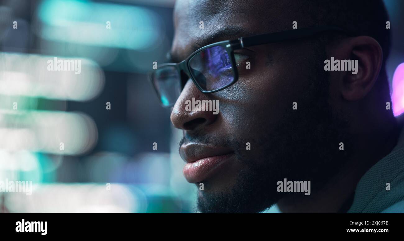 Gros plan Portrait d'homme noir travaillant sur ordinateur, lignes de langage de code reflétant sur ses lunettes. Programmeur masculin développant de nouveaux logiciels, codant, gérant un projet de cybersécurité Banque D'Images