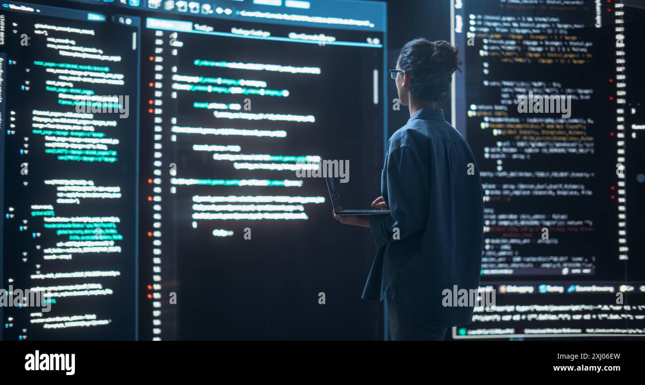 Plan d'une programmeuse travaillant dans une salle de contrôle de surveillance, entourée de grands écrans affichant des lignes de code de langage de programmation. Portrait de femme créant un logiciel, codage Banque D'Images