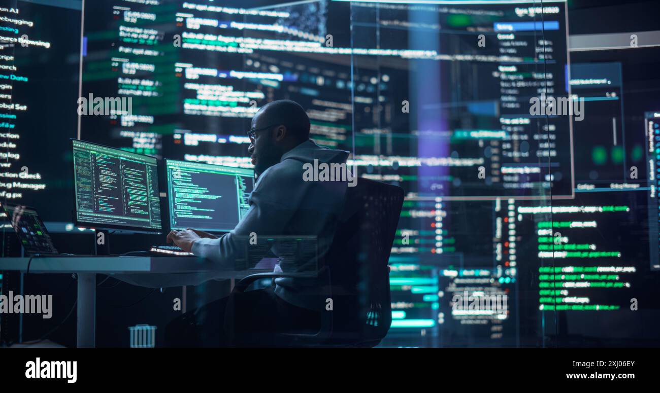 Photo d'un homme travaillant comme développeur, entouré de grands écrans affichant des lignes de code dans une salle de surveillance. Programmeur masculin noir utilisant un ordinateur de bureau, analyser des données, créer un logiciel ai Banque D'Images