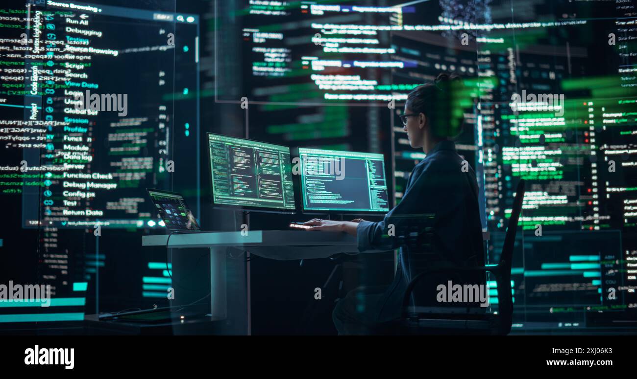 Programmeur féminin focalisé travaillant dans une salle de contrôle de surveillance, entouré de grands écrans affichant des lignes de code de langage de programmation. Portrait de femme création d'un logiciel et codage Banque D'Images
