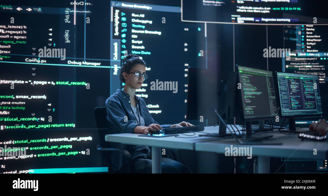 Portrait d'une femme travaillant à l'ordinateur, tapant des lignes de code qui apparaissent sur de grands écrans qui l'entourent dans la salle de surveillance sombre. Programmeur féminin créant un logiciel innovant en utilisant des données et un système ai Banque D'Images