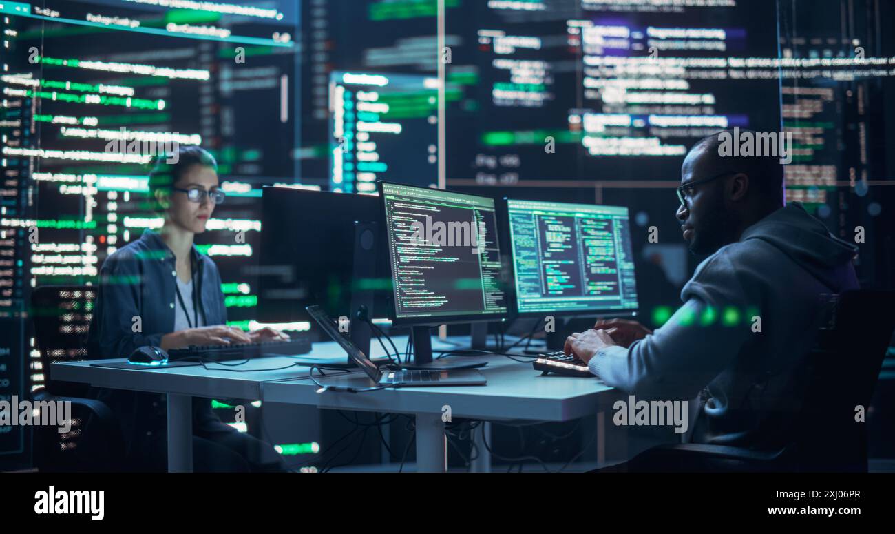 Portrait de deux développeurs divers travaillant sur des ordinateurs, en tapant des lignes de code qui apparaissent sur les grands écrans qui les entourent. Programmeurs masculins et féminins créant des logiciels innovants, corrigeant des bugs. Banque D'Images