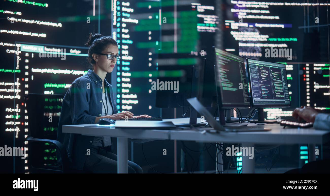 Portrait d'une femme travaillant sur un ordinateur, tapant des lignes de code qui apparaissent sur de grands écrans qui l'entourent dans une salle de surveillance. Programmeur féminin créant un logiciel innovant en utilisant des données et un système ai Banque D'Images