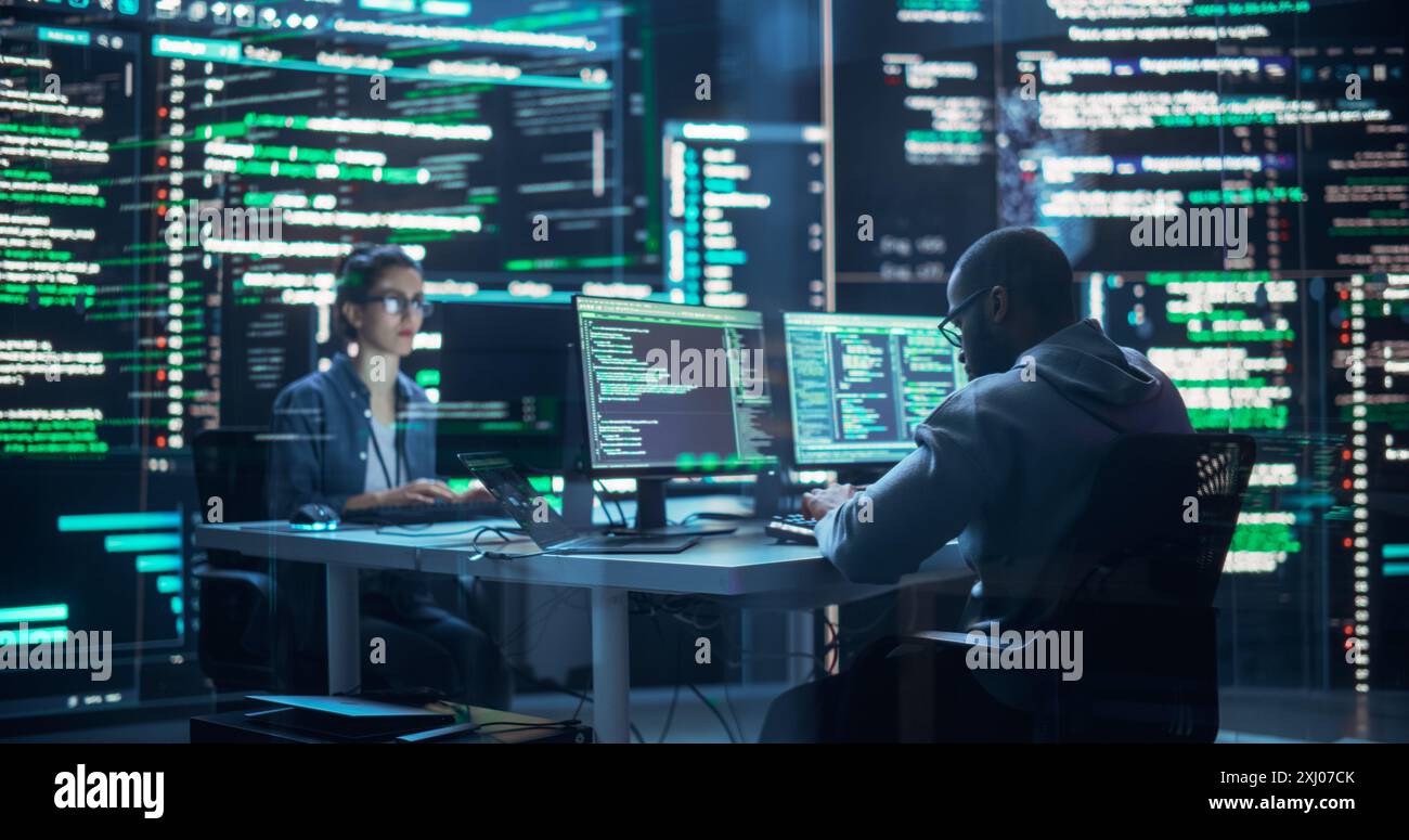 Portrait de deux programmeurs travaillant dans une salle de contrôle de surveillance, entourés de grands écrans affichant des lignes de code de langage de programmation. Portrait de divers développeurs créant un logiciel et un codage Banque D'Images