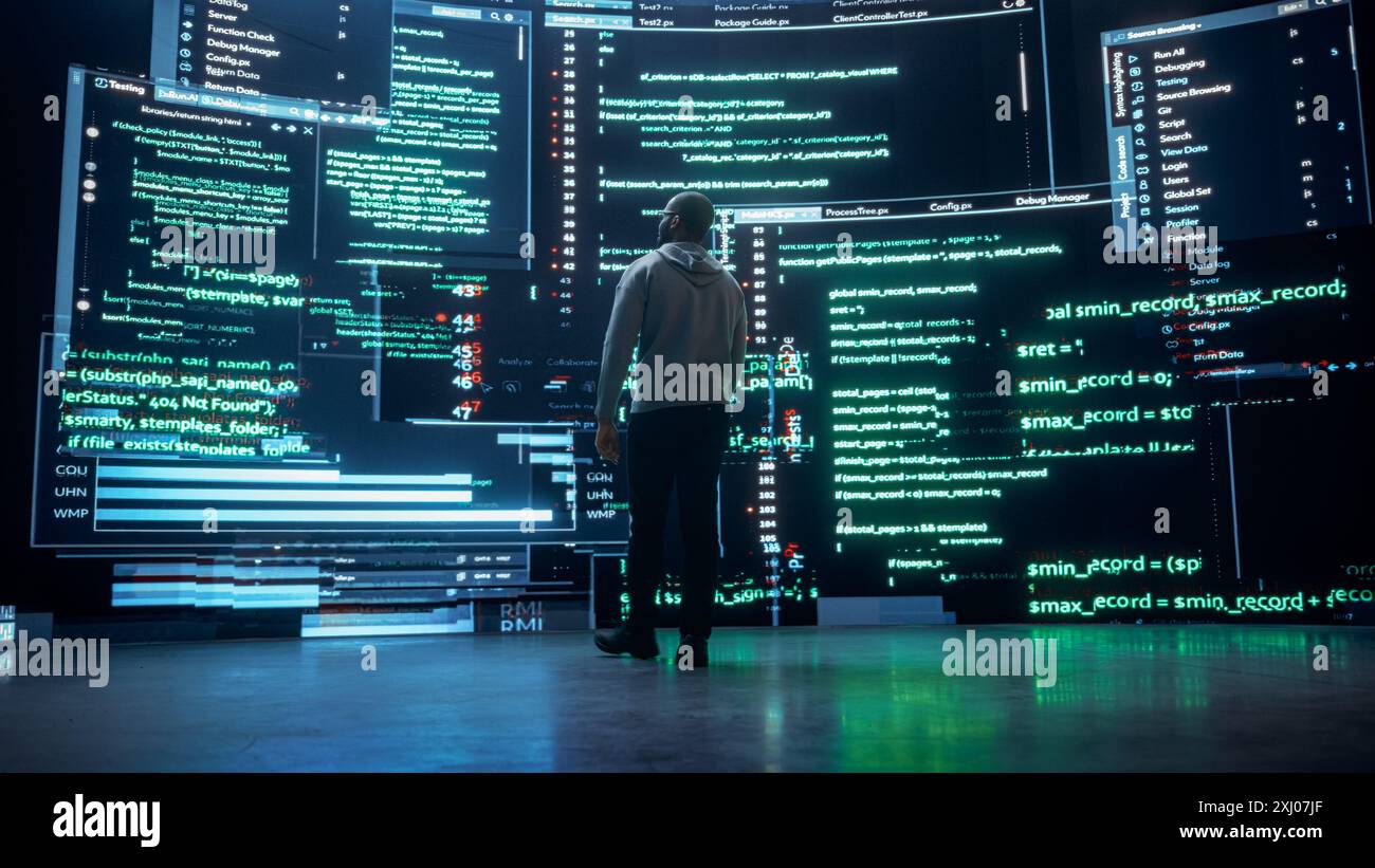 Vue arrière de jeune homme noir marchant et regardant de grands écrans numériques glitching tout en affichant des lignes de code. Pirate professionnel franchissant le système de protection de cybersécurité, changeant le code Banque D'Images