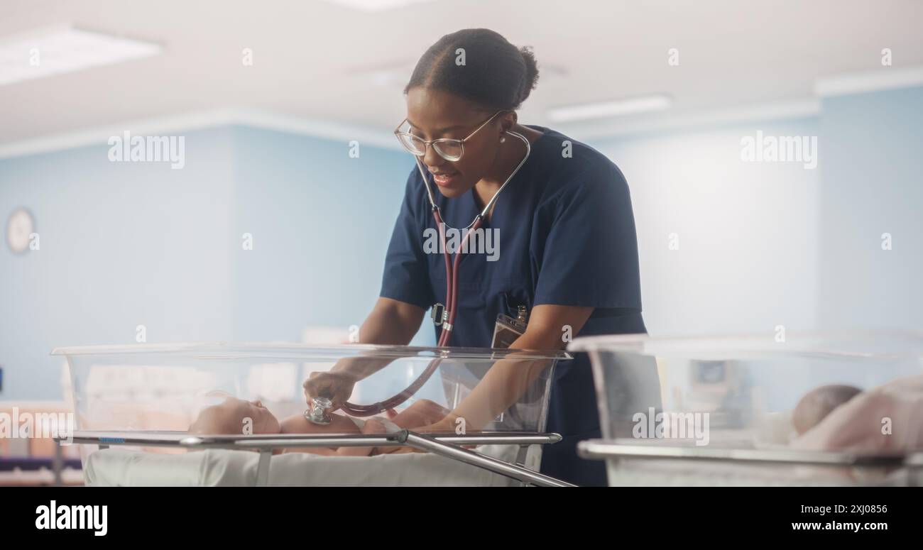 Happy Professional infirmière fournissant des soins 24 heures sur 24 à un bébé prématuré récupéré dans une unité de soins intensifs néonatals. Médecin féminin africain vérifiant sur un enfant, en utilisant stéthoscope dans la clinique de la pépinière Banque D'Images