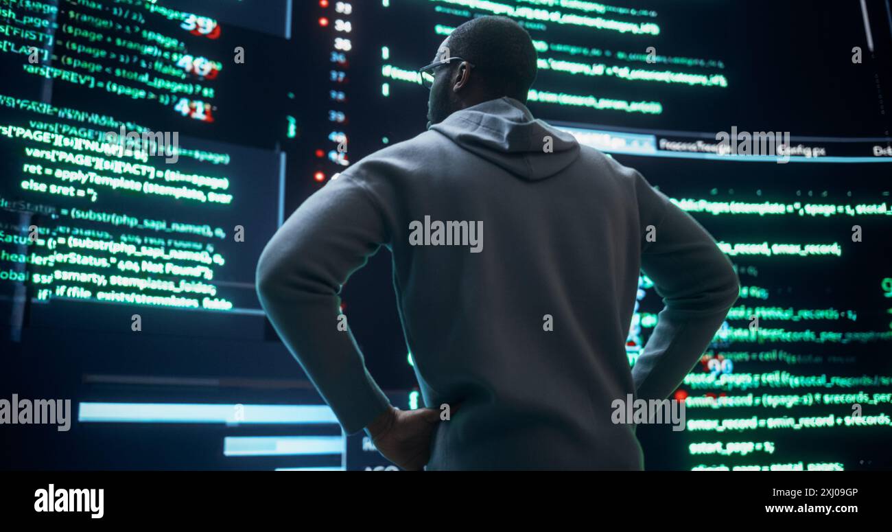 Portrait de jeune homme noir regardant de grands écrans numériques glitching tout en affichant des lignes de code. Inquiet programmeur professionnel fixant un bogue, traitant avec le plantage du système, pensant à des solutions Banque D'Images