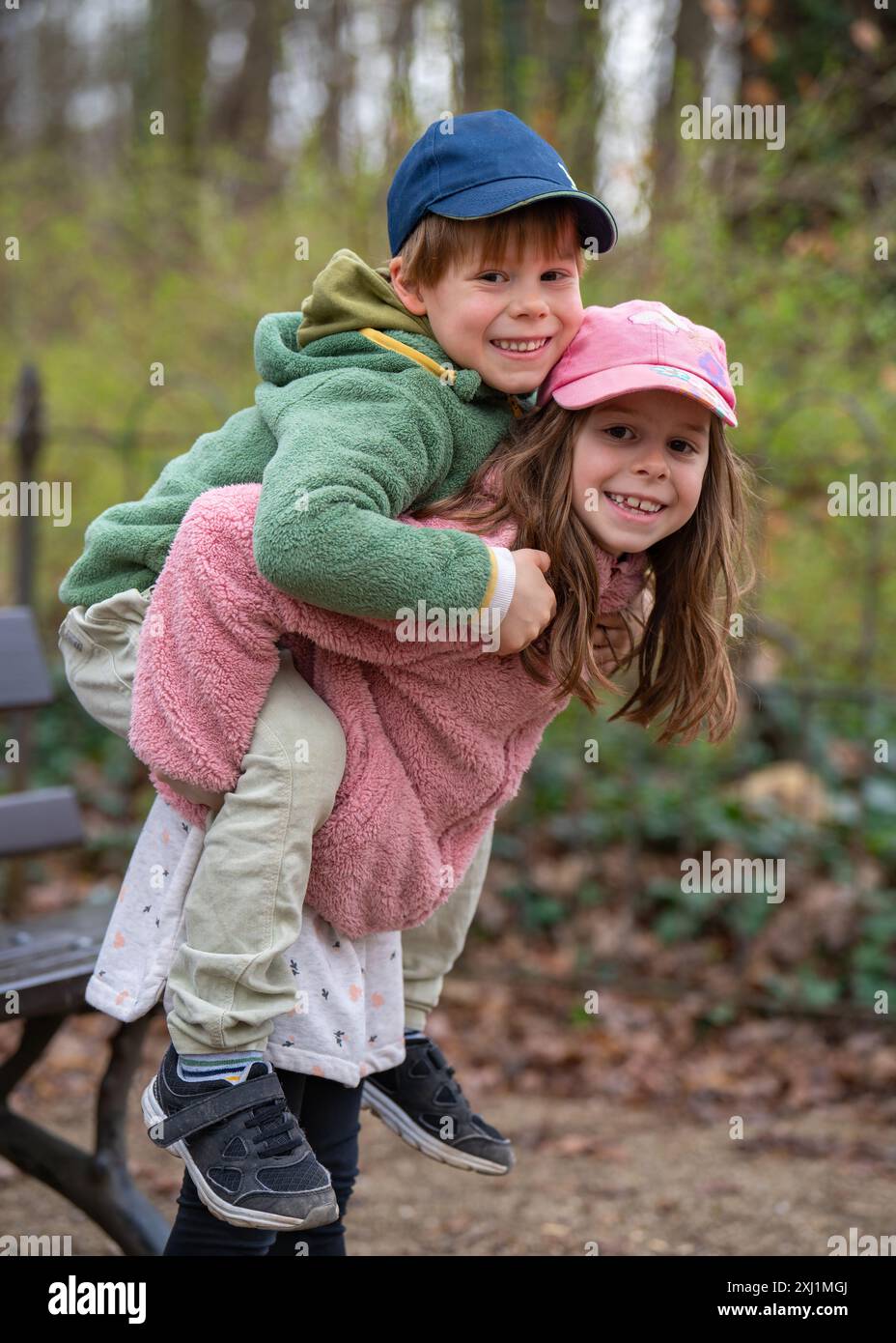 Joli frère et sœur bavardant dehors. Une fille tient un garçon sur le dos. Jeux amusants dans la nature. Enfance joyeuse et heureuse Banque D'Images