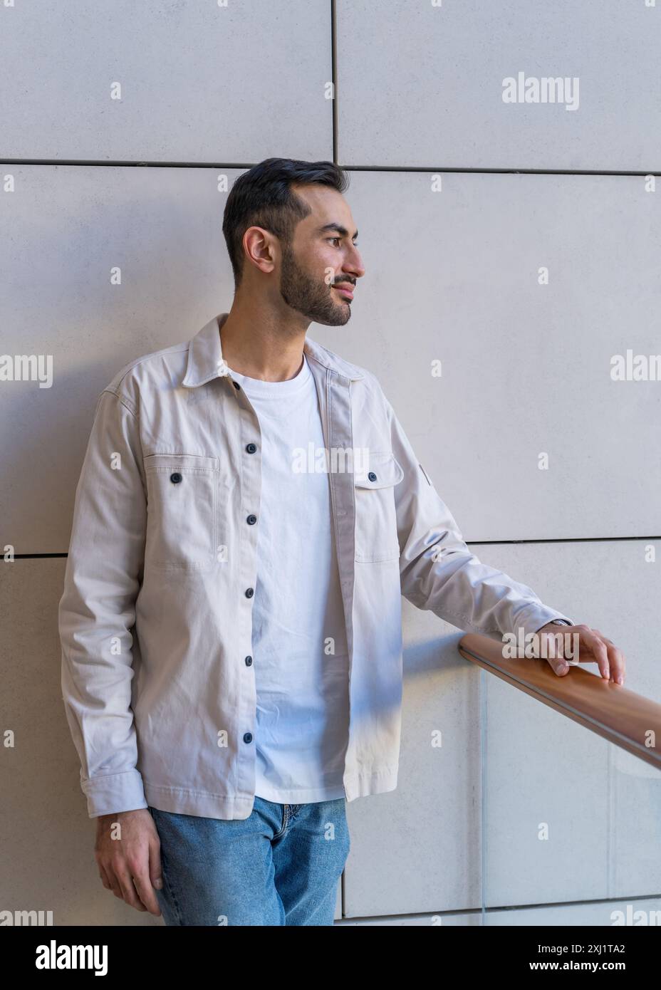 Portrait en gros plan d'un jeune et beau homme asiatique avec une barbe. Debout près du mur Banque D'Images