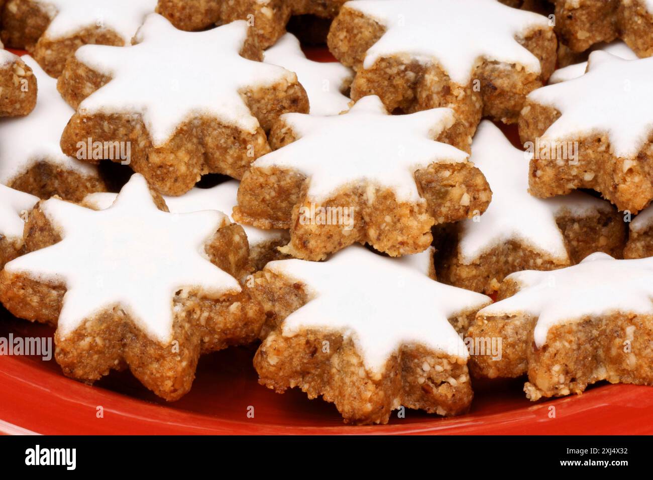 Gros plan de quelques biscuits étoilés à la cannelle (en allemand Zimtsterne), des biscuits de Noël typiquement allemands et suisses sur une assiette rouge Banque D'Images