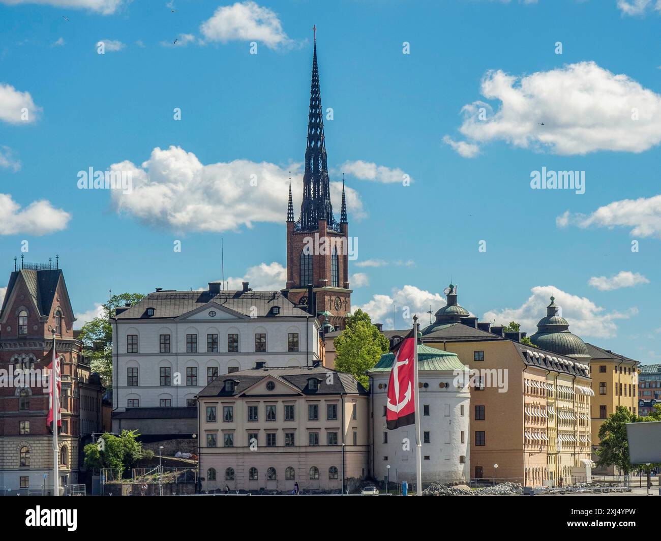 Bâtiment et église sur le front de mer avec un drapeau et un ciel nuageux, stockholm, suède Banque D'Images