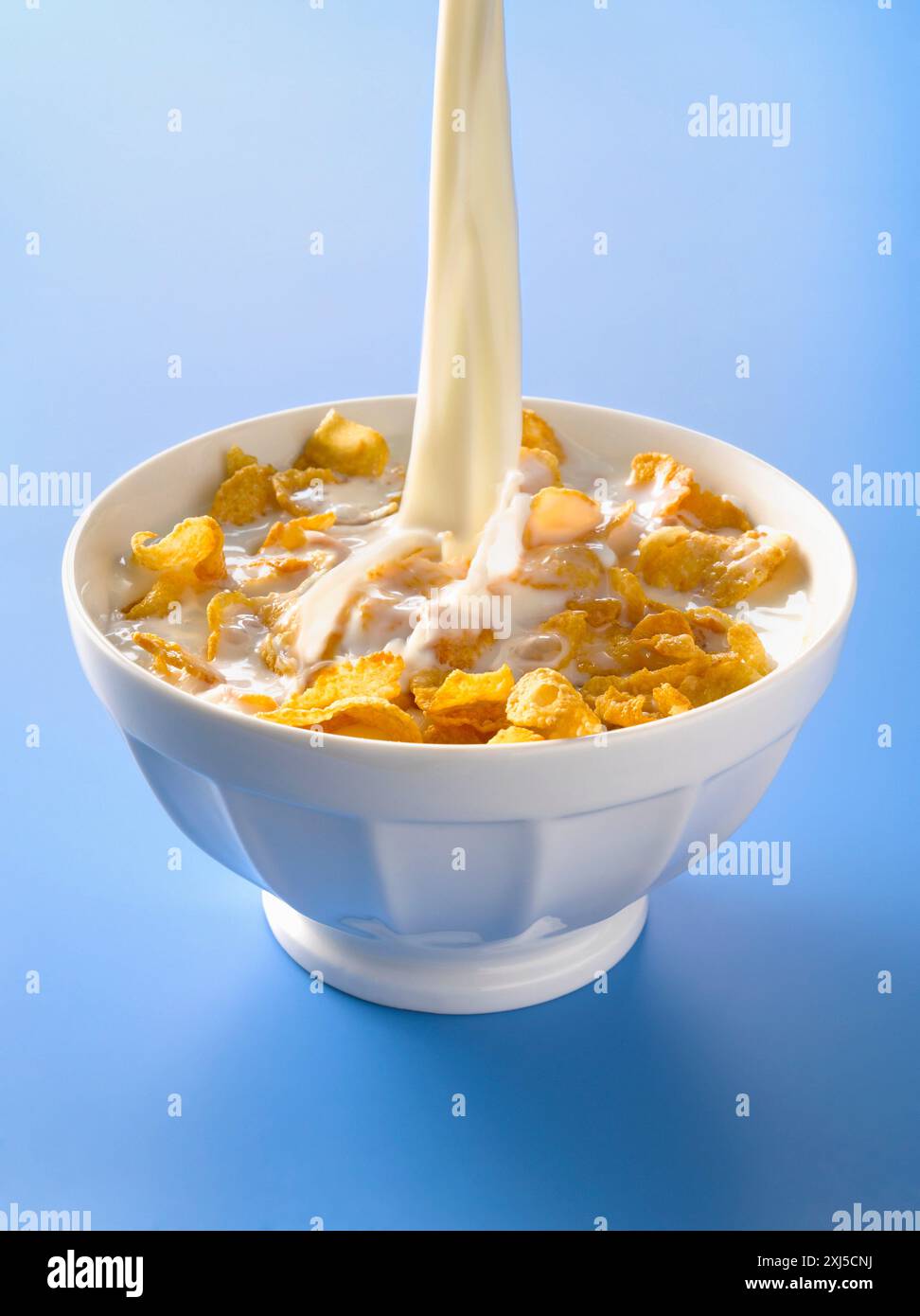 Verser le lait dans un bol de cornflakes Banque D'Images