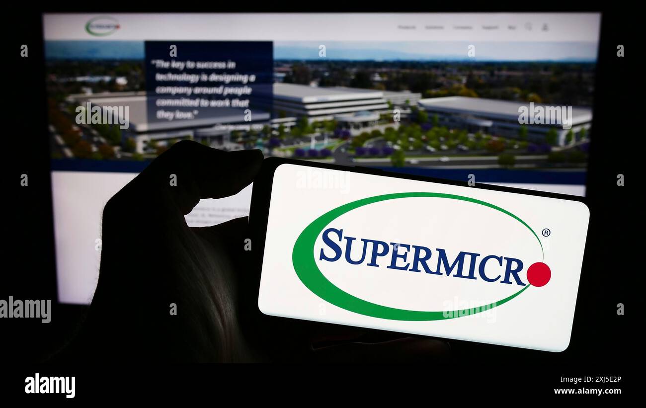 Stuttgart, Allemagne, 02-13-2024 : personne tenant un smartphone avec le logo de la société américaine Super Micro Computer Inc (Supermicro) devant le site. Mise au point Banque D'Images