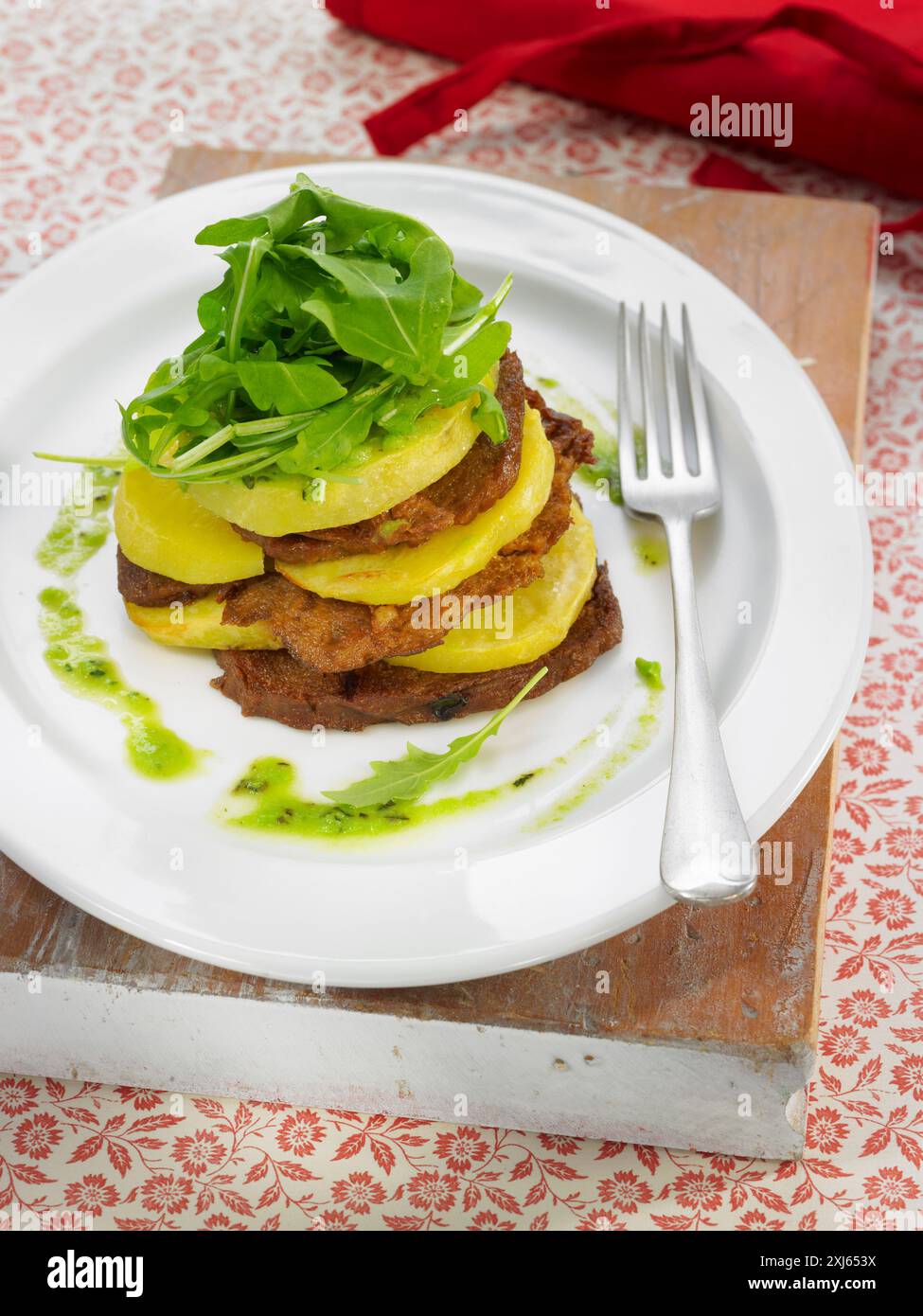 Seitan et pommes de terre en couches, purée de pois, menthe et laitue roquette Banque D'Images