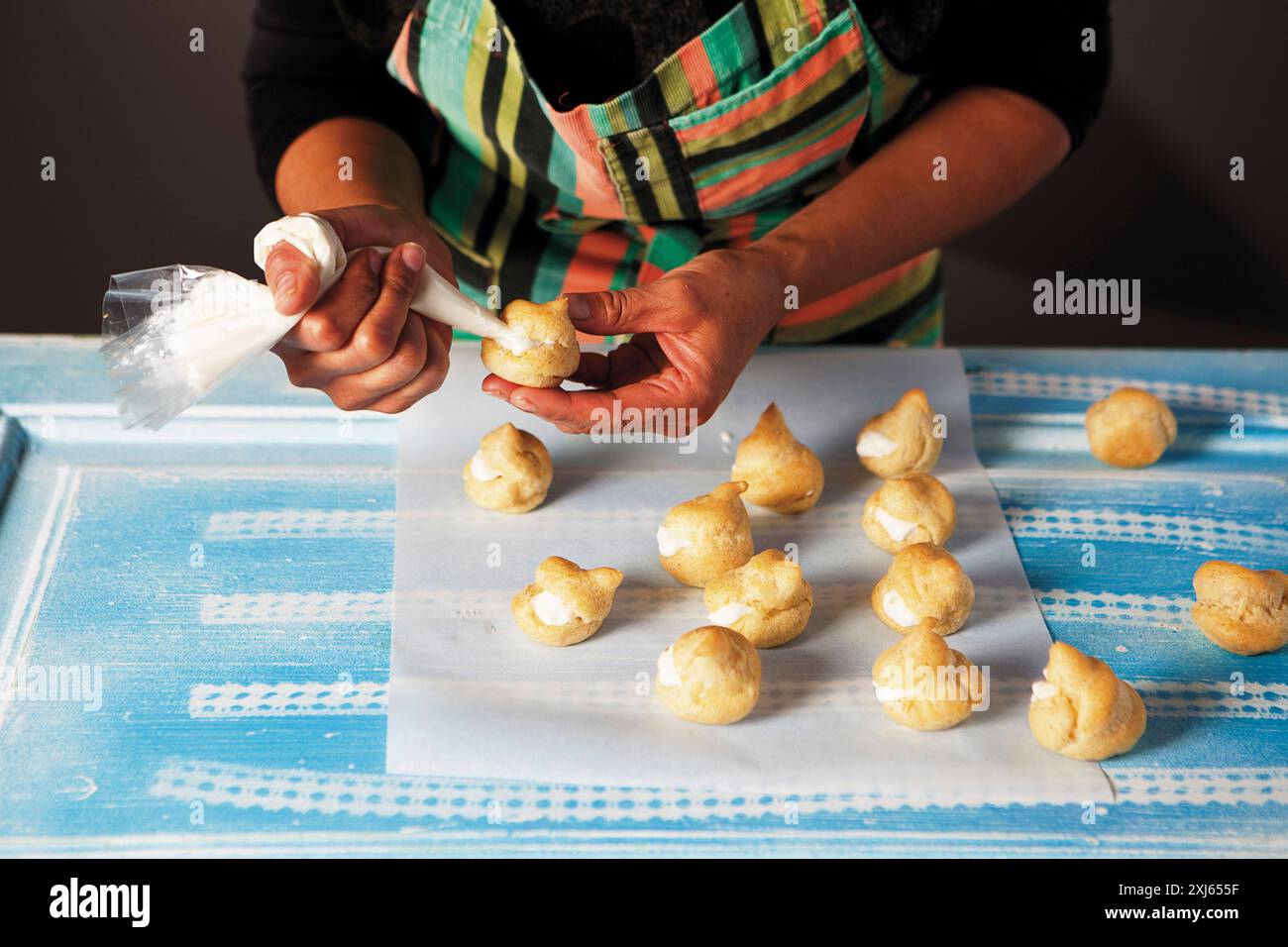 Après la cuisson, remplissez les pâtisseries feuilletées de crème à l'aide d'un sac à passepoil Banque D'Images