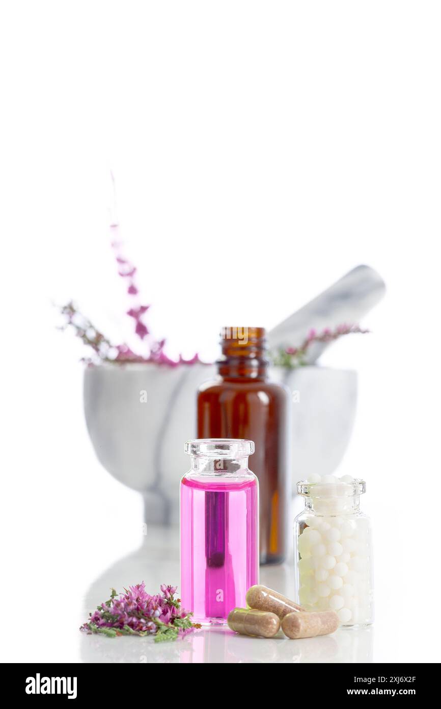 Ambiance aromathérapie avec granules, bruyère, mortier de marbre et pilon et petites bouteilles d'eau florale sur fond blanc Banque D'Images