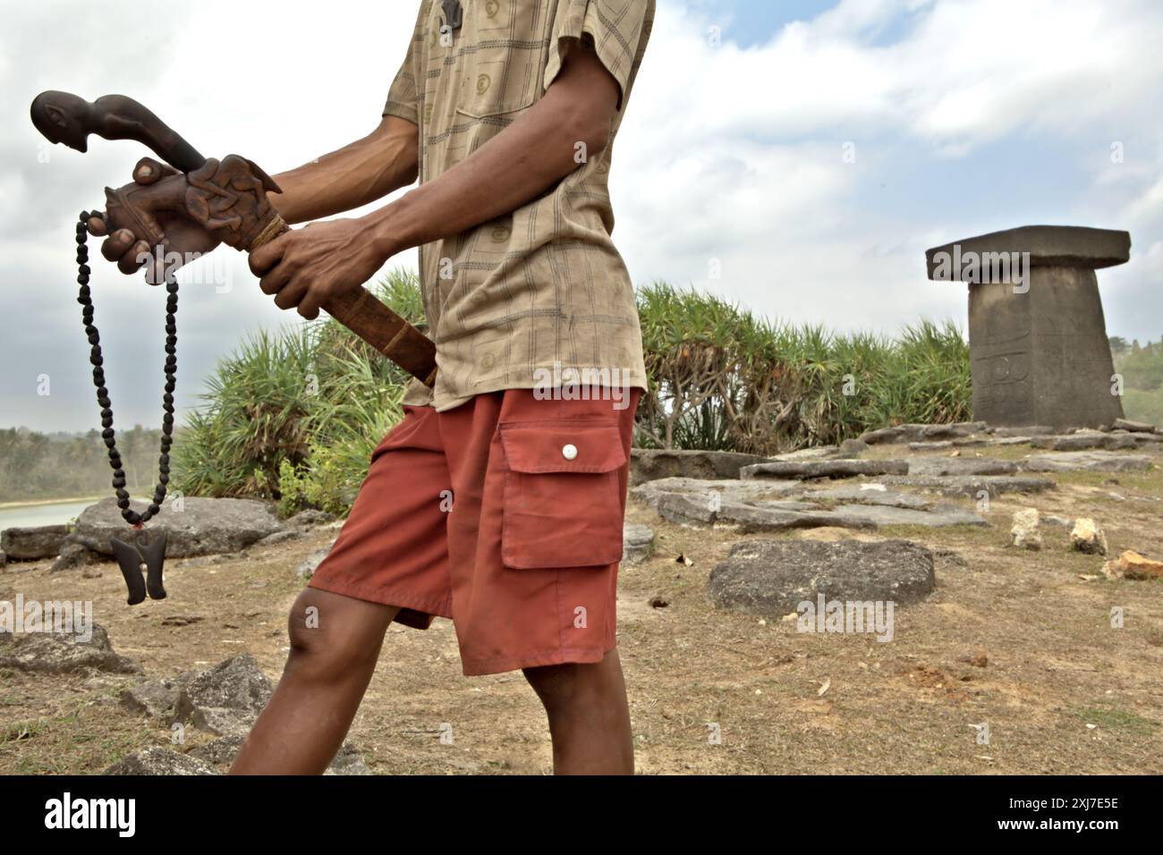 Un villageois vend un collier traditionnel et une machette avec des sculptures traditionnelles sur sa gaine et sa poignée comme souvenirs, alors qu'il se tient près d'un tombeau mégalithique sur la plage de Ratenggaro, un village indigène situé dans le sud-ouest de Sumba, est de Nusa Tenggara, Indonésie. Lors d’une réunion de l’Assemblée générale en décembre 2023, l’Organisation des Nations Unies (ONU) a exprimé ses préoccupations au sujet du détournement et de l’utilisation abusive du patrimoine culturel des peuples autochtones. L’ONU réaffirme que les peuples autochtones ont le droit de maintenir, contrôler, protéger et développer leur patrimoine culturel, leurs savoirs traditionnels et... Banque D'Images