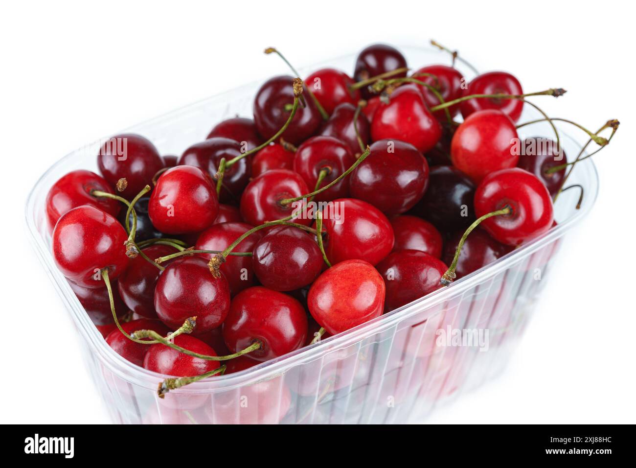 Pile de baies de cerise douce fraîche mûre, fruit dans un récipient en plastique transparent isolé sur fond blanc. Cerises douces biologiques rouges en boîte, santé Banque D'Images