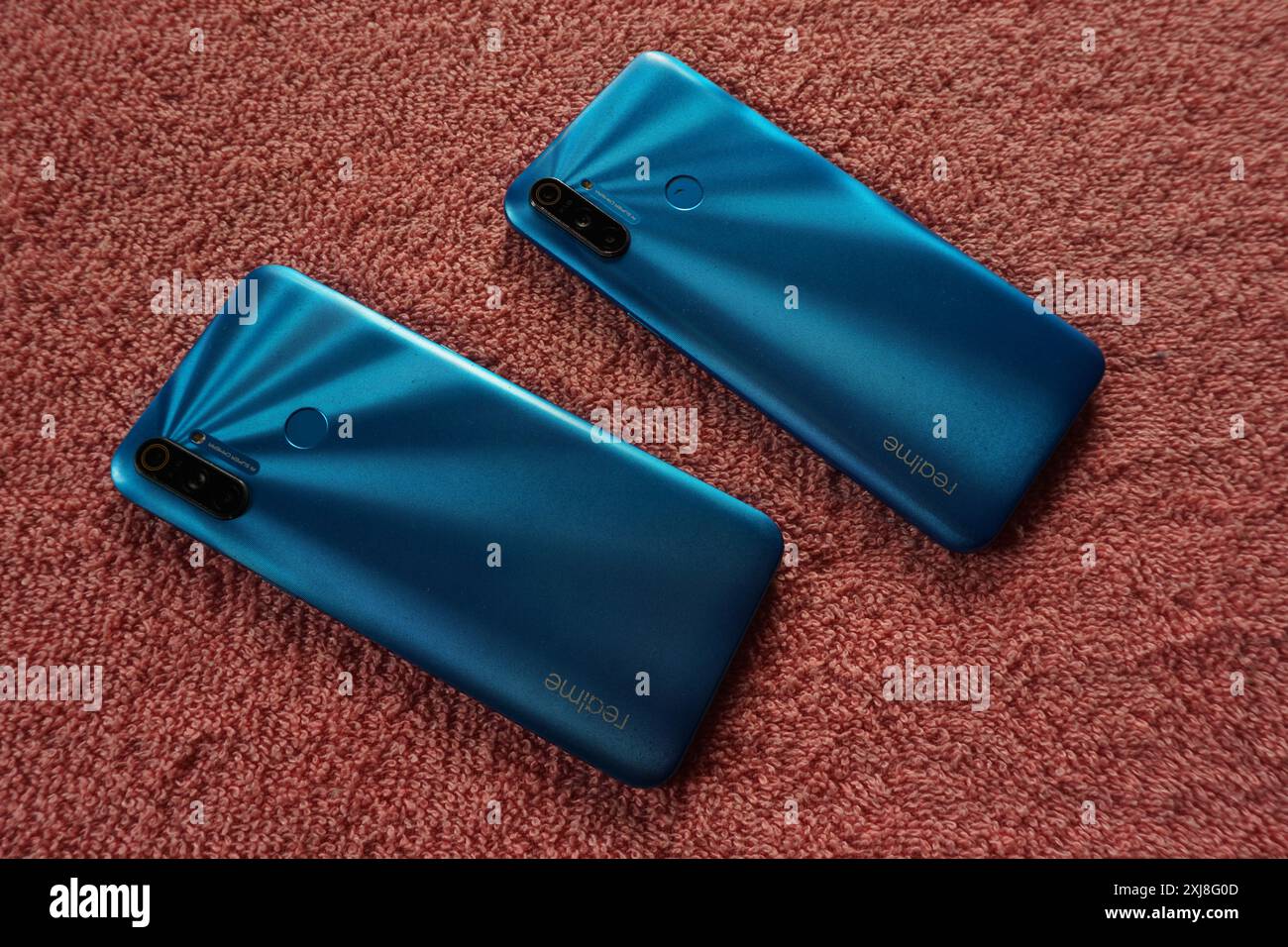 Terengganu, Malaisie - 2 août 2024 : gros plan arrière des smartphones realme bleus sur fond rouge. Téléphone milieu de gamme Realme. Deux appareils realme. Banque D'Images