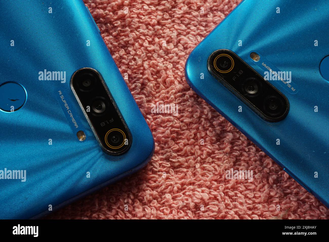 Terengganu, Malaisie - 2 août 2024 : gros plan de l'objectif de l'appareil photo realme smartphone sur fond rouge. Deux appareils realme. Téléphones realme du panneau arrière. Banque D'Images